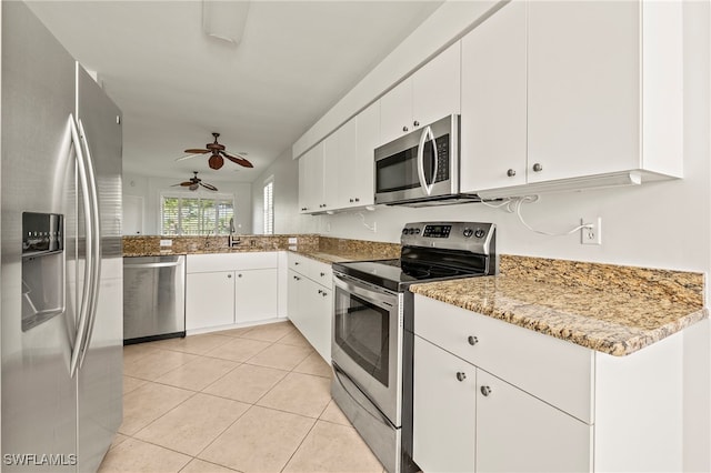 kitchen featuring light tile patterned floors, ceiling fan, stainless steel appliances, light stone countertops, and white cabinets