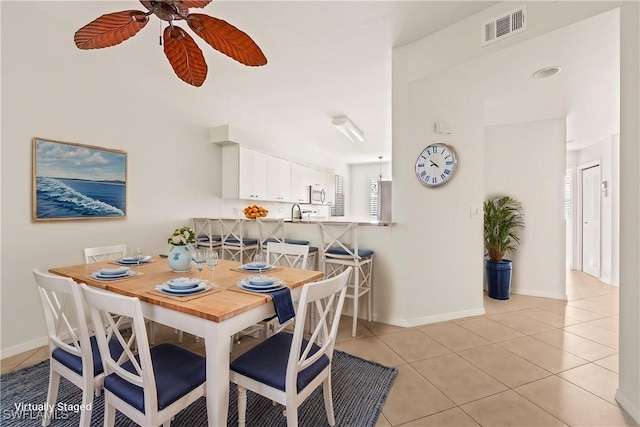 tiled dining room with ceiling fan and sink