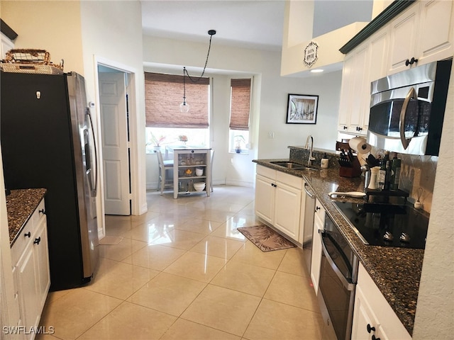 kitchen with appliances with stainless steel finishes, white cabinetry, hanging light fixtures, and sink