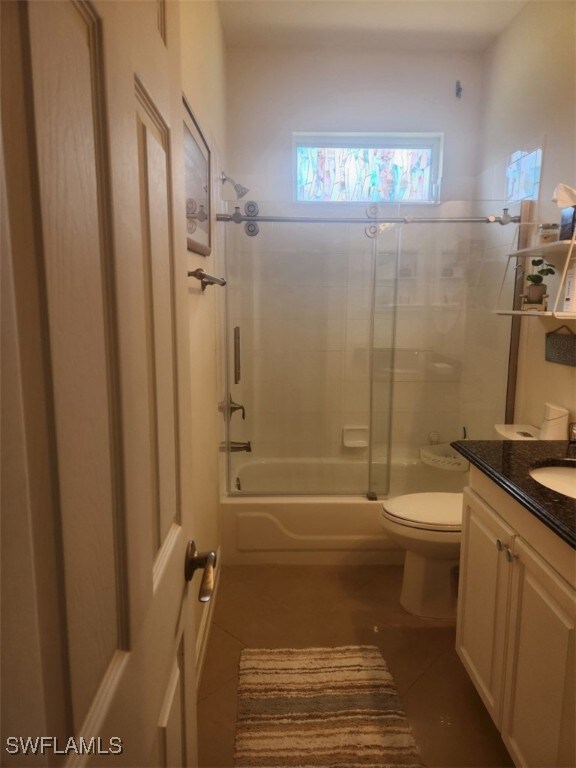 full bathroom with shower / bath combination with glass door, vanity, toilet, and tile patterned flooring