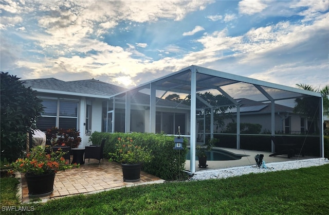 rear view of property with a lanai, a patio area, and a yard