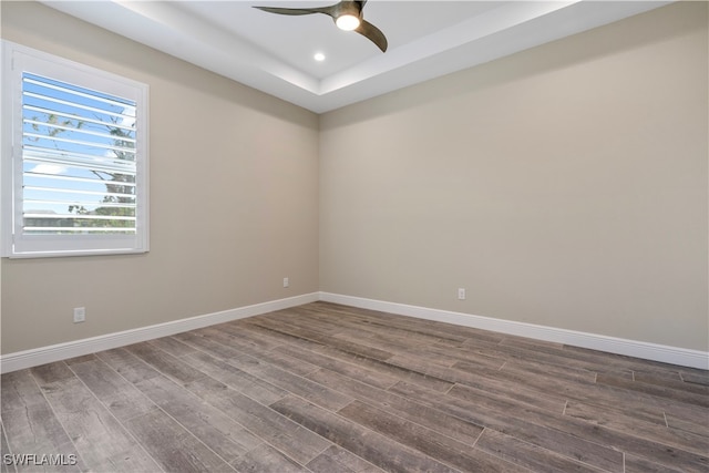 spare room with ceiling fan, wood-type flooring, and a raised ceiling