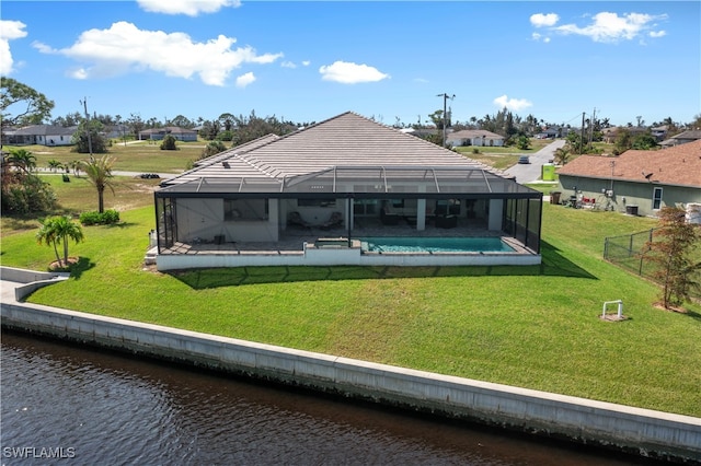 back of property with a water view, a lanai, and a yard