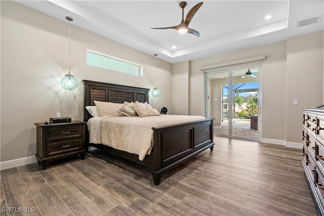 bedroom featuring a raised ceiling, ceiling fan, dark hardwood / wood-style floors, and access to outside