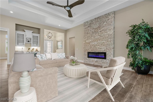 living room featuring ceiling fan with notable chandelier and a stone fireplace