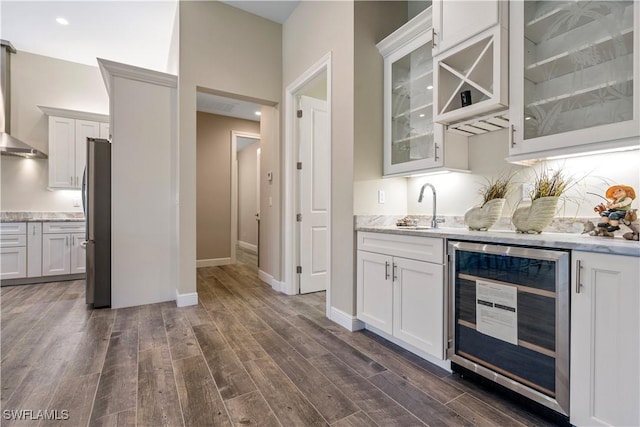 kitchen with white cabinets, sink, wall chimney exhaust hood, beverage cooler, and stainless steel fridge