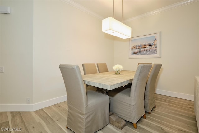 dining space with light hardwood / wood-style flooring and ornamental molding