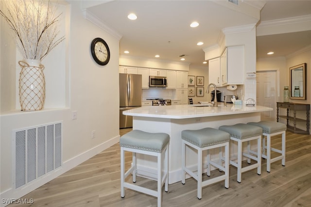 kitchen featuring backsplash, appliances with stainless steel finishes, light hardwood / wood-style flooring, and white cabinets