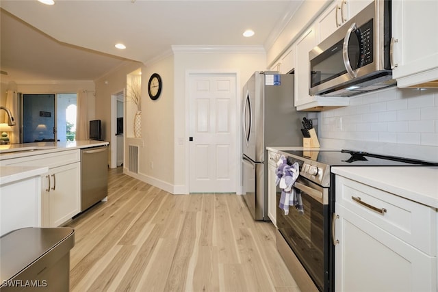 kitchen with crown molding, white cabinetry, light hardwood / wood-style flooring, and stainless steel appliances