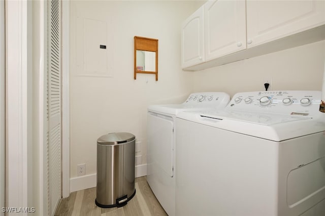 laundry room with cabinets, electric panel, light wood-type flooring, and washing machine and clothes dryer