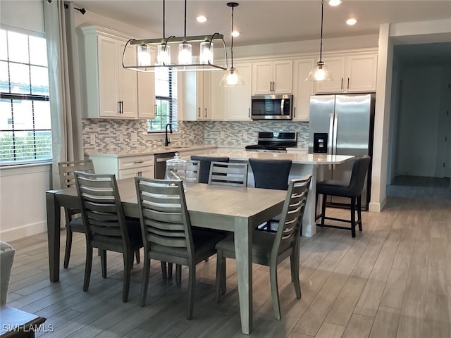 kitchen with appliances with stainless steel finishes, hanging light fixtures, and white cabinets