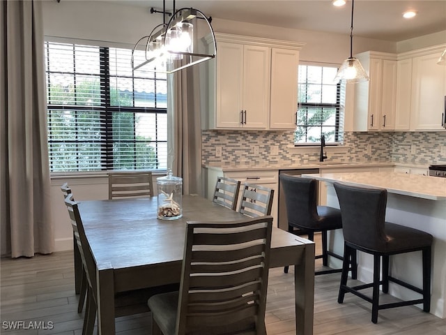 dining space featuring light hardwood / wood-style floors, sink, and an inviting chandelier