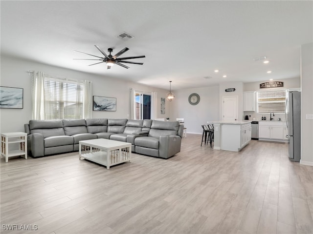 living room featuring light hardwood / wood-style floors, ceiling fan, and sink