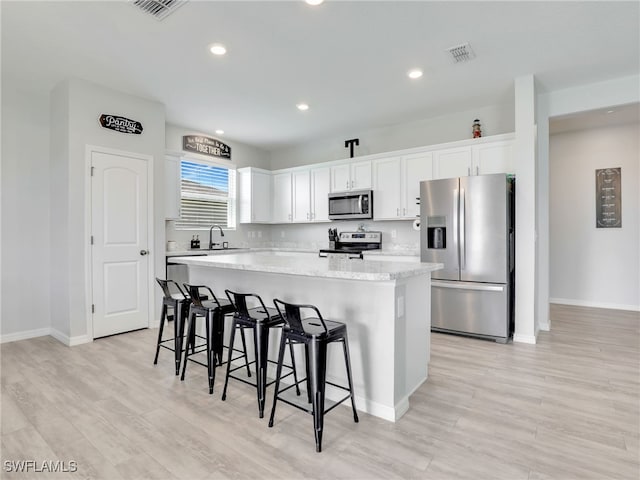 kitchen with stainless steel appliances, a kitchen island, and white cabinetry