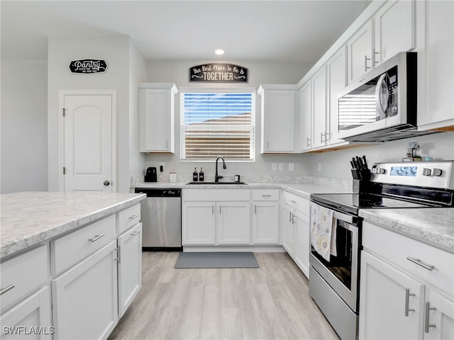 kitchen featuring sink, white cabinets, light hardwood / wood-style floors, and appliances with stainless steel finishes