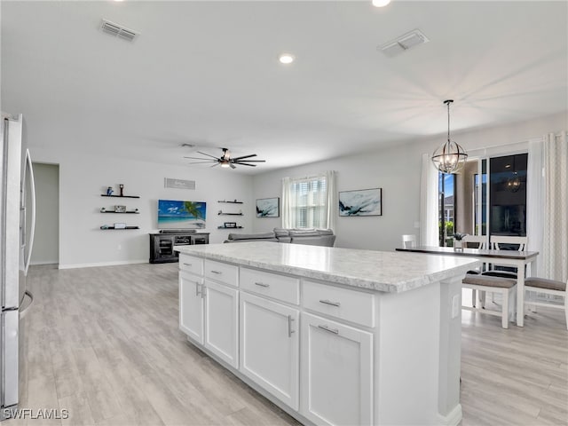 kitchen with white cabinetry, a center island, stainless steel fridge, pendant lighting, and light wood-type flooring