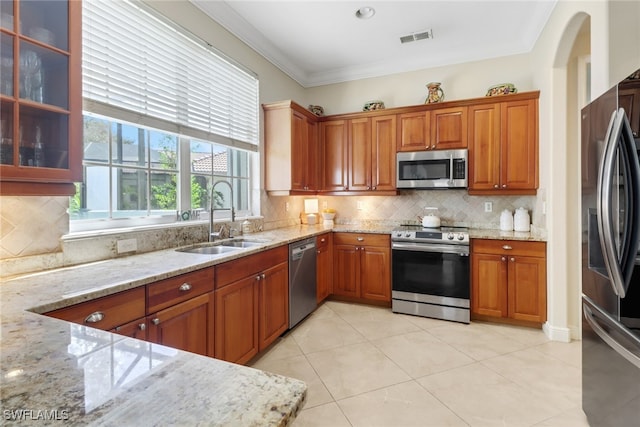 kitchen with stainless steel appliances, light stone countertops, sink, and tasteful backsplash