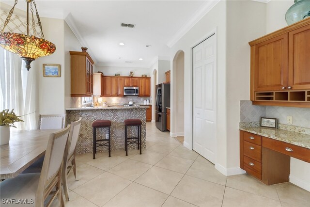 kitchen with crown molding, hanging light fixtures, stainless steel appliances, and tasteful backsplash