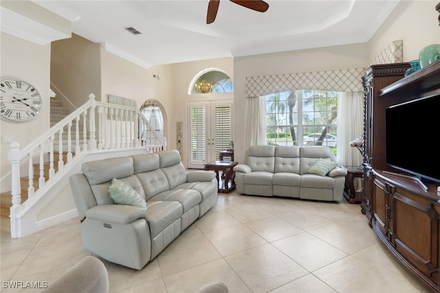 living room with ceiling fan, a tray ceiling, light tile patterned flooring, and crown molding