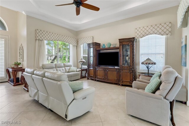 living room featuring ceiling fan, light tile patterned floors, and a raised ceiling