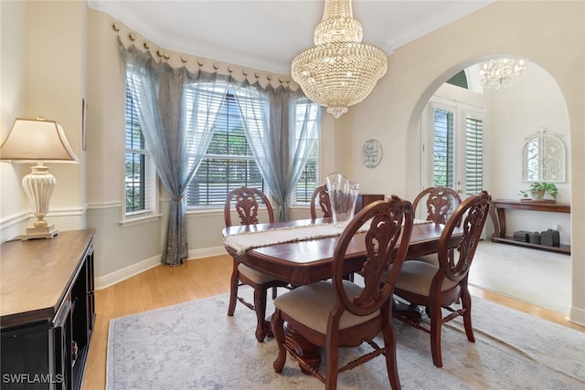 dining room with a notable chandelier, ornamental molding, and light wood-type flooring