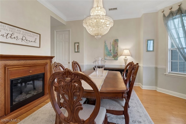 dining area with light hardwood / wood-style floors, a notable chandelier, and ornamental molding