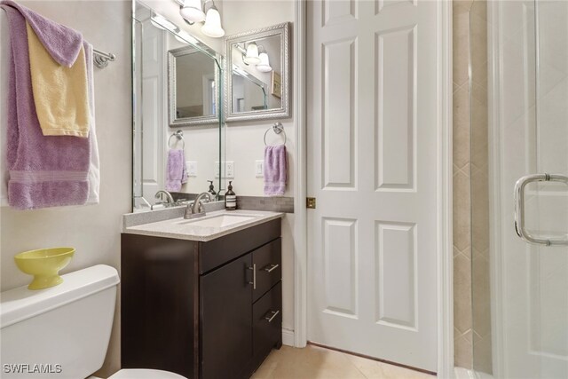 bathroom with toilet, walk in shower, vanity, and tile patterned flooring