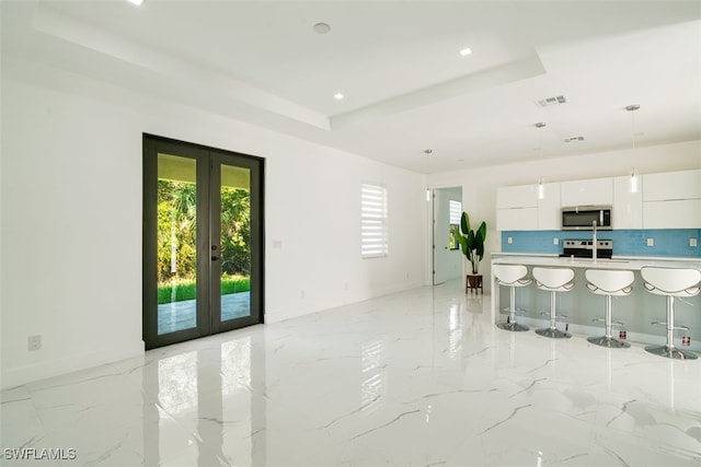 kitchen featuring tasteful backsplash, appliances with stainless steel finishes, a breakfast bar, white cabinetry, and french doors