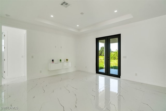 unfurnished room with french doors and a raised ceiling