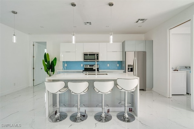 kitchen with tasteful backsplash, appliances with stainless steel finishes, sink, decorative light fixtures, and white cabinets