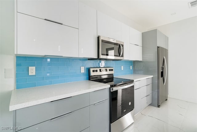 kitchen with white cabinetry, gray cabinetry, stainless steel appliances, and backsplash