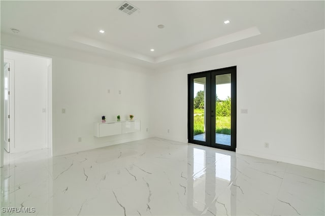 spare room featuring french doors and a raised ceiling