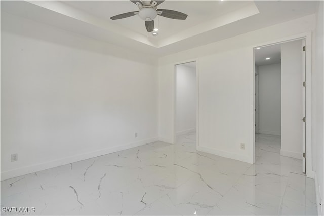 spare room with ceiling fan and a raised ceiling