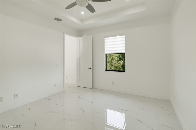 unfurnished room featuring ceiling fan and a tray ceiling