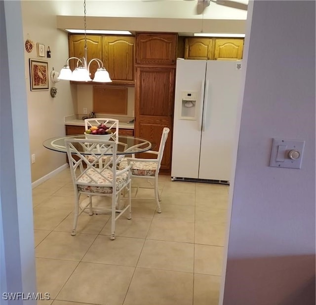 kitchen featuring white fridge with ice dispenser, light tile patterned flooring, hanging light fixtures, and a notable chandelier