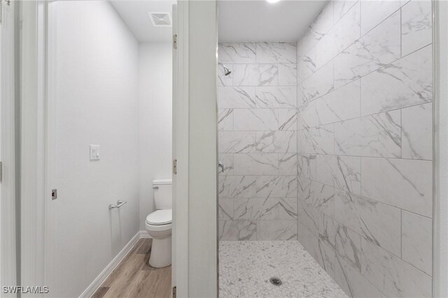 164 Thornton Ave S, Lehigh Acres, FL 33974 - bathroom featuring hardwood / wood-style flooring, tiled shower, and toilet