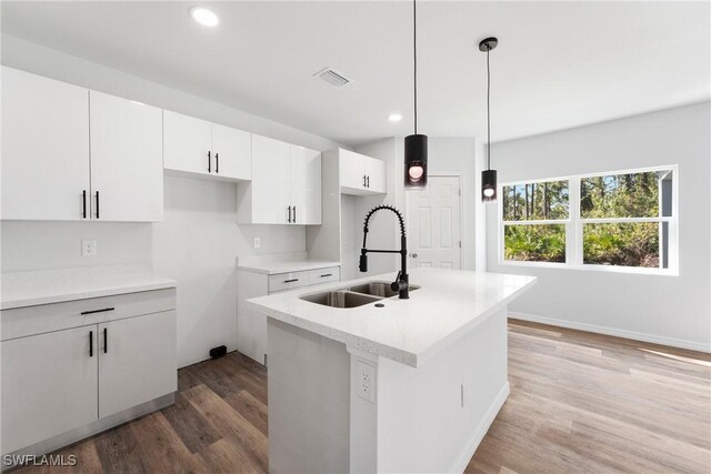 164 Thornton Ave S, Lehigh Acres, FL 33974 - kitchen featuring hardwood / wood-style floors, decorative light fixtures, sink, white cabinets, and a kitchen island with sink
