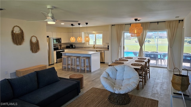 living room featuring sink, light hardwood / wood-style flooring, and ceiling fan