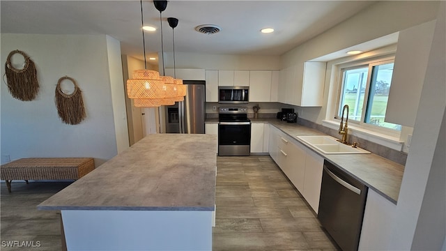 kitchen with sink, pendant lighting, white cabinets, and stainless steel appliances