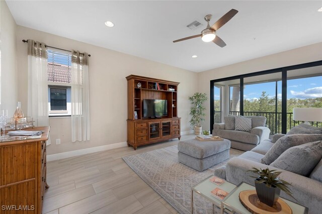 living room with ceiling fan, a healthy amount of sunlight, and light hardwood / wood-style flooring