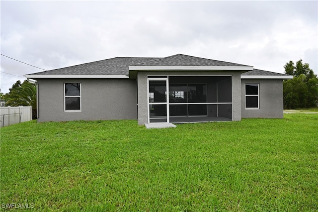 rear view of house featuring a lawn and a sunroom