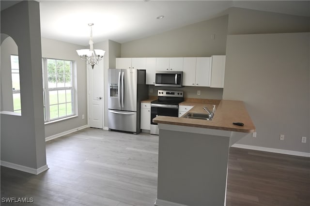 kitchen with kitchen peninsula, lofted ceiling, white cabinetry, decorative light fixtures, and stainless steel appliances