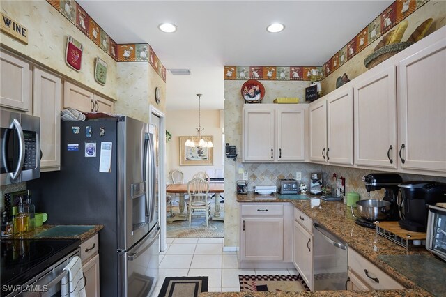 kitchen with appliances with stainless steel finishes, white cabinetry, dark stone counters, and light tile patterned floors