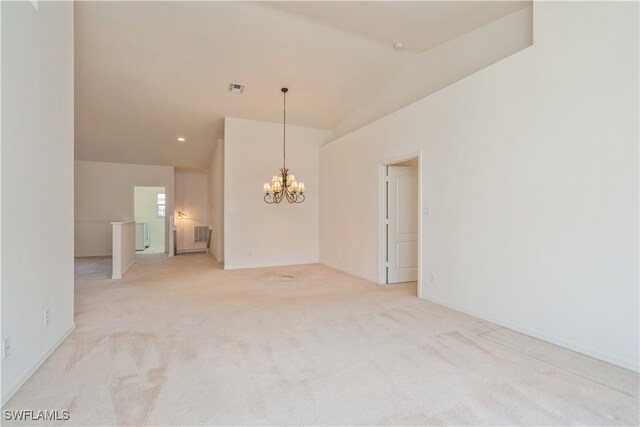 spare room featuring lofted ceiling, light colored carpet, and a notable chandelier