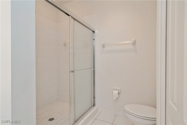 bathroom with toilet, tile patterned floors, and a shower with door