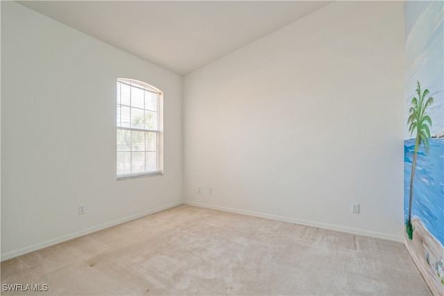 spare room featuring vaulted ceiling and light carpet