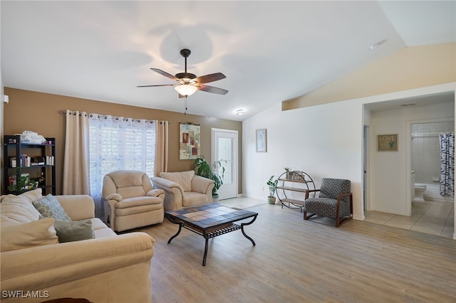 living room with light hardwood / wood-style floors, vaulted ceiling, and ceiling fan