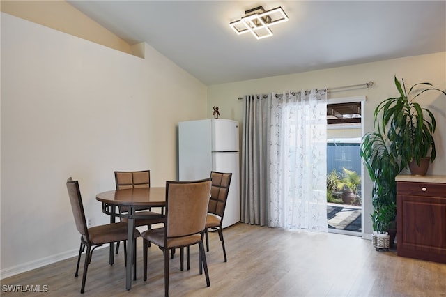 dining space featuring vaulted ceiling and light hardwood / wood-style flooring