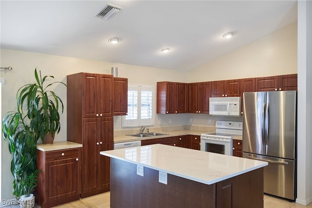 kitchen featuring white appliances, sink, a center island, lofted ceiling, and light tile patterned floors