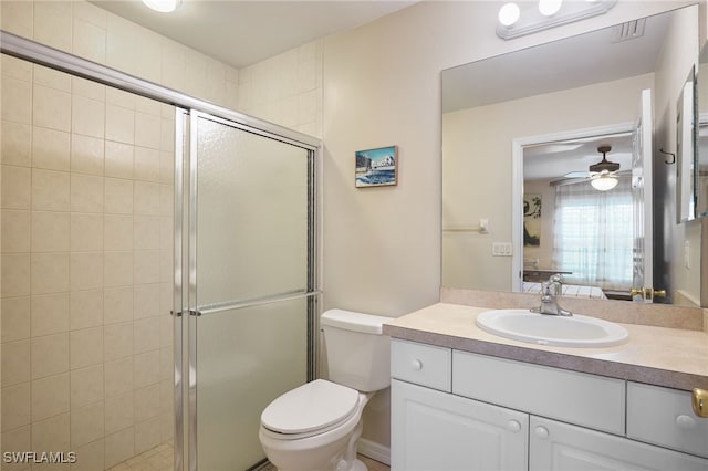 bathroom with vanity, toilet, a shower with shower door, and ceiling fan